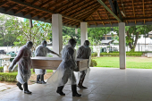 Municipal workers carry the coffin of an unclaimed body of a COVID-19 victim to a crematorium in Colombo in this December 10 photo [Lakruwan Wanniarachchi/AFP]