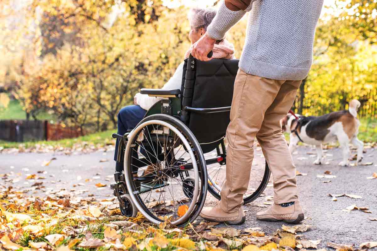 senior man pushing senior woman in wheelchair