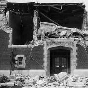 A building after an earthquake has crumbled the roof and brick walls, the interior is now visible.