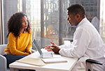 Doctor taking notes while talking to patient