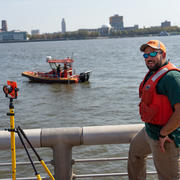 USGS scientist surveys water levels on the Delaware River while streamflow measurements are made by boat.