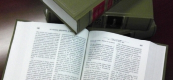 An open lawbook with a closed lawbook touching the top corner of the left open page. 