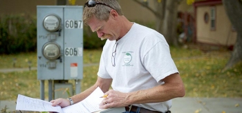 A worker reviews paperwork while standing next to a control box. 