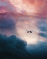 White plane flying through clouds. 