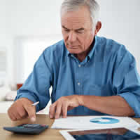 older man in his kitchen using a calcupator