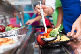 Close up of vegetables; students choosing food in school cafeteria