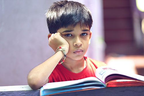 Sad looking young boy with a book