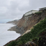 Photo of a coastal cliff with an apartment building right at the edge of the cliff.