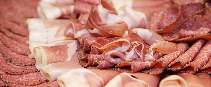 Close-up shot of a platter of cold cuts including salami, pepperoni and cured ham.
