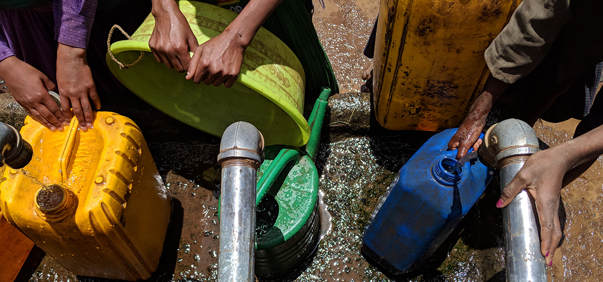 People filling water containers with water.