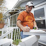 Photo of a weatherization worker writing notes for an energy audit on a clipboard.