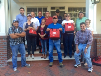 Group of people standing and facing the camera outside of a building.