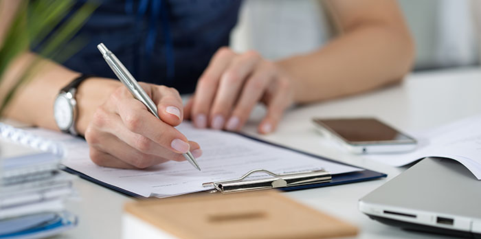 Woman writing on clipboard sitting at her office