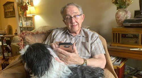 Veteran checks his phone while seated with dog