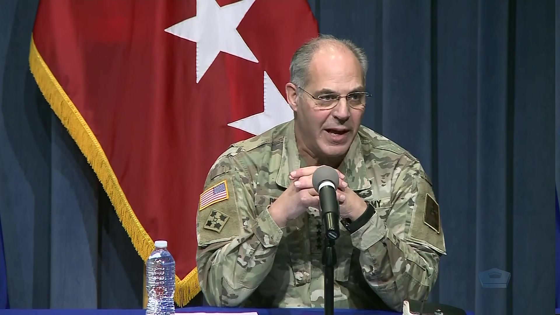 A soldier sits and speaks into a microphone.