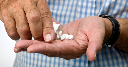 Person placing pills in hand from prescription bottle