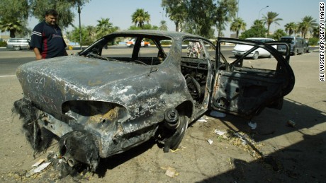 An Iraqi looks 24 September 2007, at a burnt car on the site where Blackwater guards who were escorting US embassy officials opened fire in the western Baghdad neighbourhood of Yarmukh,  a shootout which left, 16 September 2007,  nine civilians and a policeman dead. Iraq said today that it will await the outcome of an investigation into the killing of 10 people during the shootout before taking any action against the company. AFP PHOTO/ALI YUSSEF (Photo credit should read ALI YUSSEF/AFP/Getty Images)