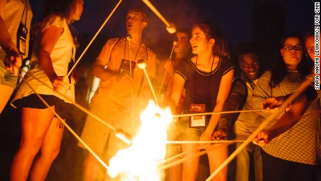 Campers at the Tuesday&#39;s Child retreat roast marshmallows over a fire together.