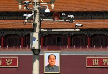 Security cameras on pole above photo of Mao Zedong (© Andy Wong/AP Images)