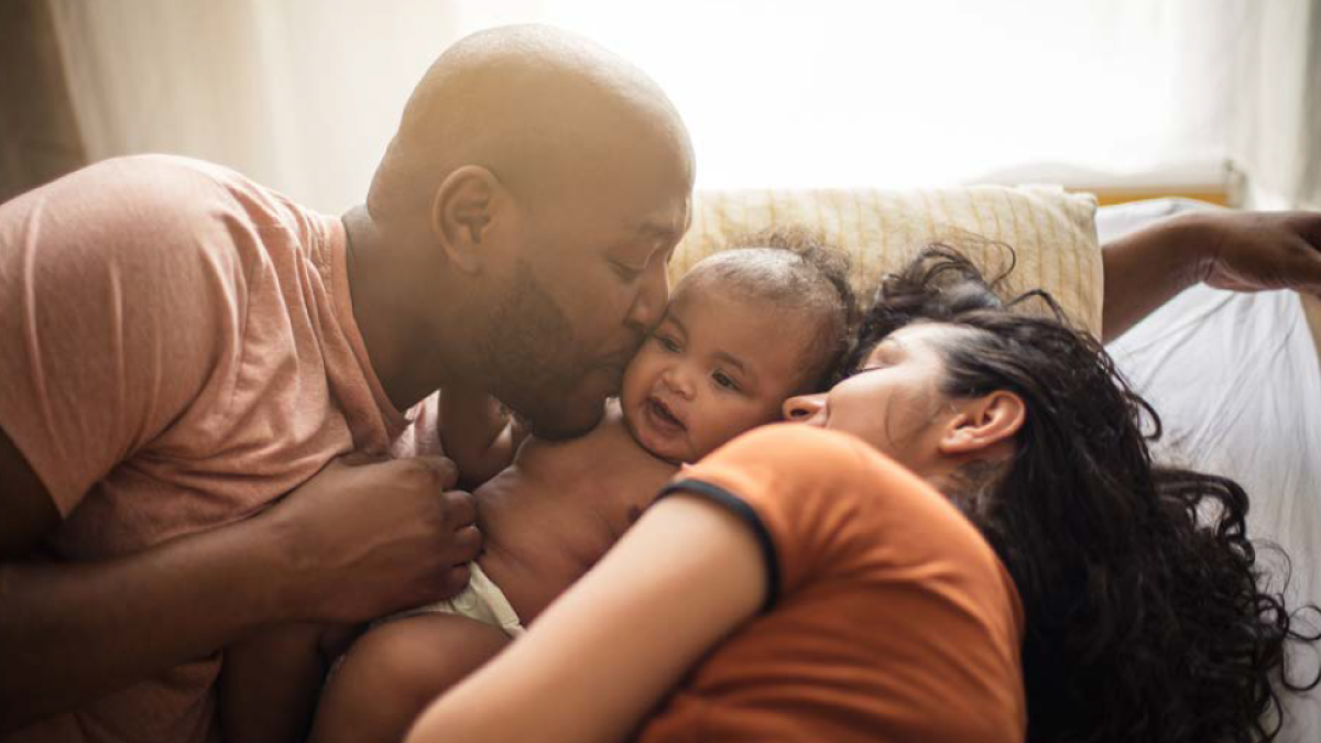 The figure is a photo of a couple kissing a child on the cheeks.