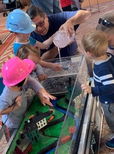 A member of the FEMA Building Science team uses a flood table to demonstrate the effects of flooding to young attendees at the National Building Museum’s Big Build Community Day.