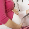 Pregnant woman and her healthcare provider, with a focus on the woman’s stomach.