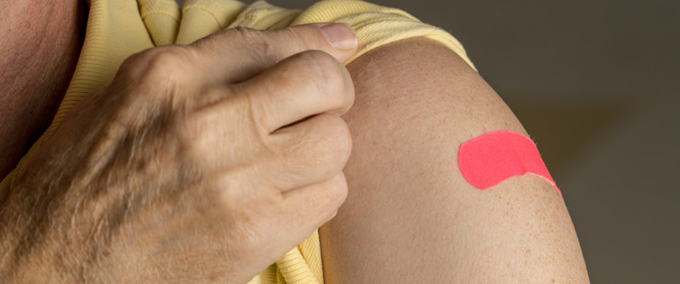 senior man holding up shirt sleeve after getting vaccine