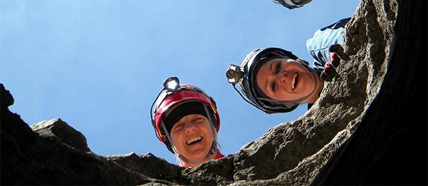 Women with hard hats looking down a hole