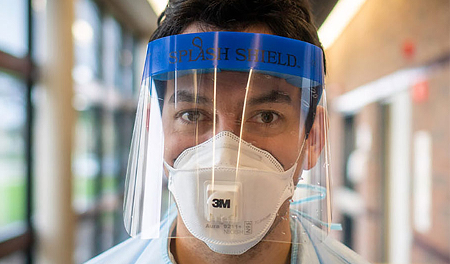 hombre con una mascarilla y un protector facial de plástico