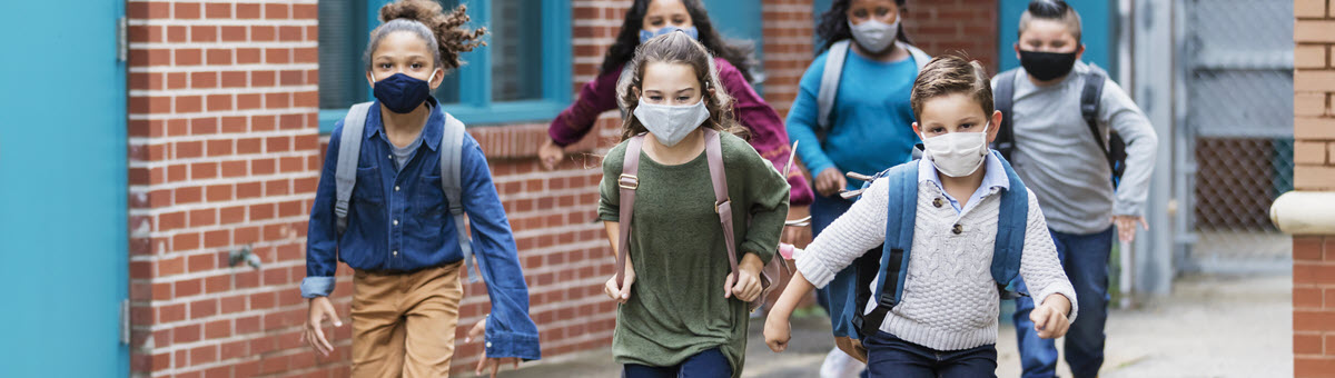 마스크를 쓰고 학교 건물 밖에서 달리는 아이들