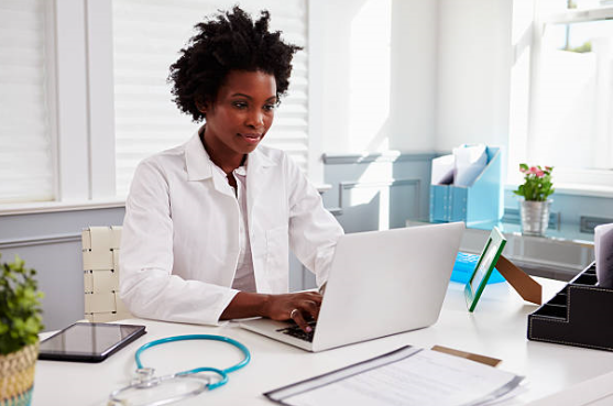 a doctor sitting at her desk watching a webinar