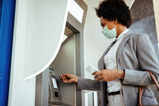 Người phụ nữ đang đưa thẻ ghi nợ hoặc thẻ tín dụng vào máy ATM