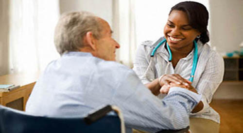 A nurse sits with a patient.