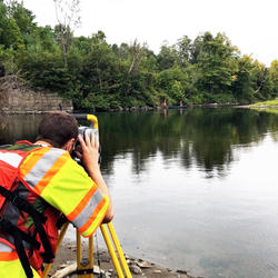 Hydrologic Technician Gunther Schletter takes a channel measurement using a Total Station on a river near St. Johnsbury, VT.