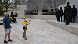 Volunteer talking to a visitor in a memorial plaza