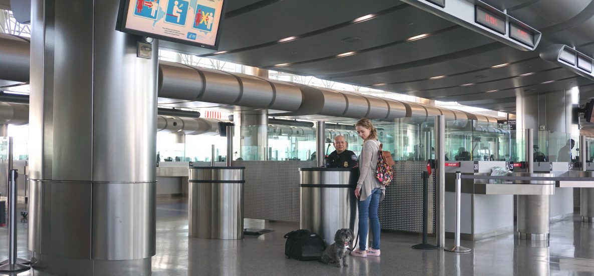 photo of a traveler with dog going through Customs at airport; talking to CBP agent