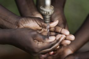 Hands collecting running water from a faucet