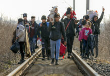 Group of people walking along railroad tracks