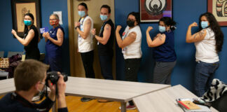 Line of women and men showing their arms after getting COVID-19 vaccination (© Karen Ducey/Getty Images)