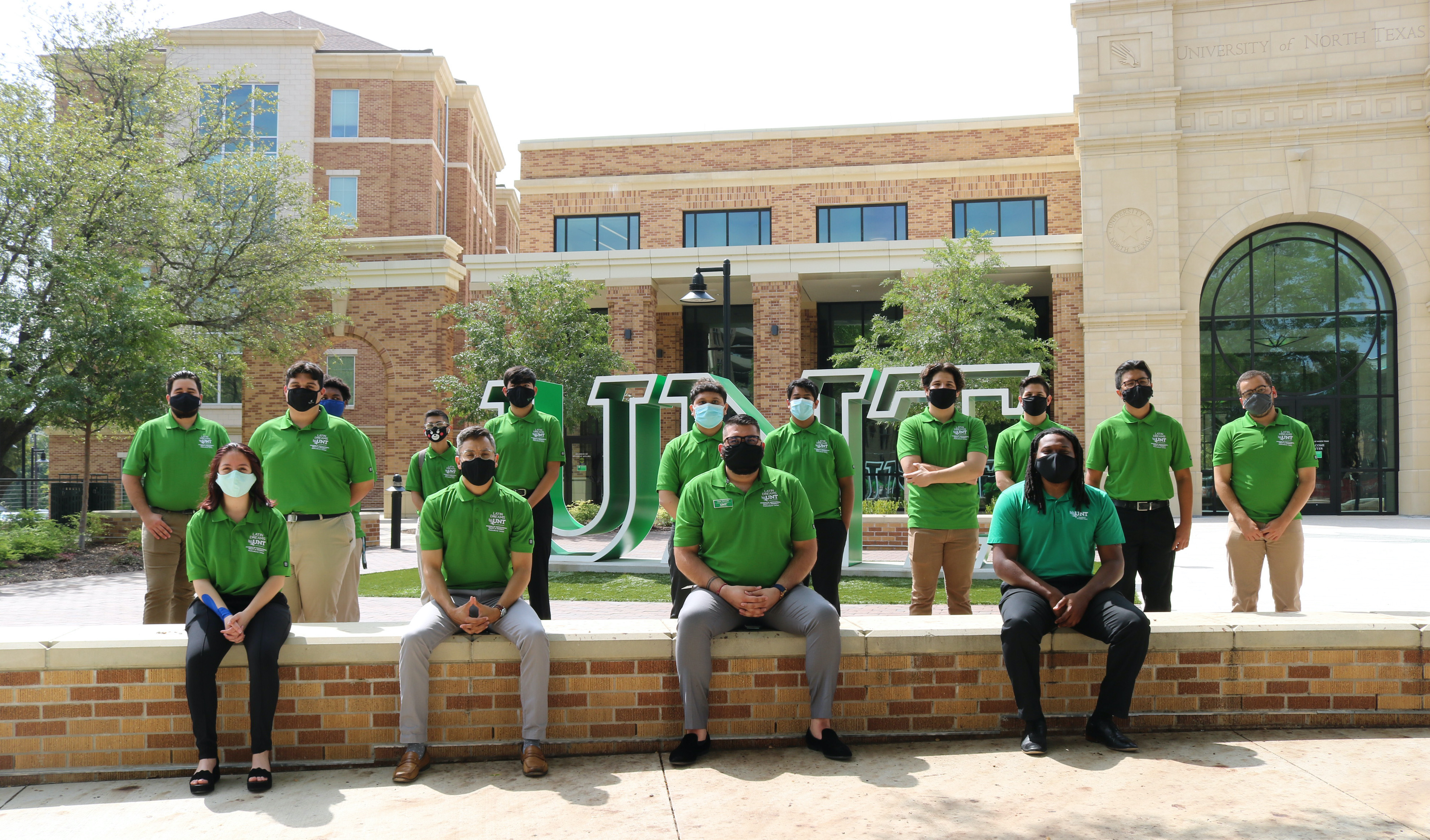 Latin Dreams mentors and students sitting in front of UNT sign